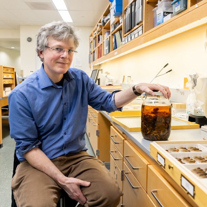 John Cooley, poses with a jar of cicada specimens currently kept in UConn's Biodiversity Research Collections on Friday, Feb. 9, 2024. (Sydney Herdle/UConn Photo)